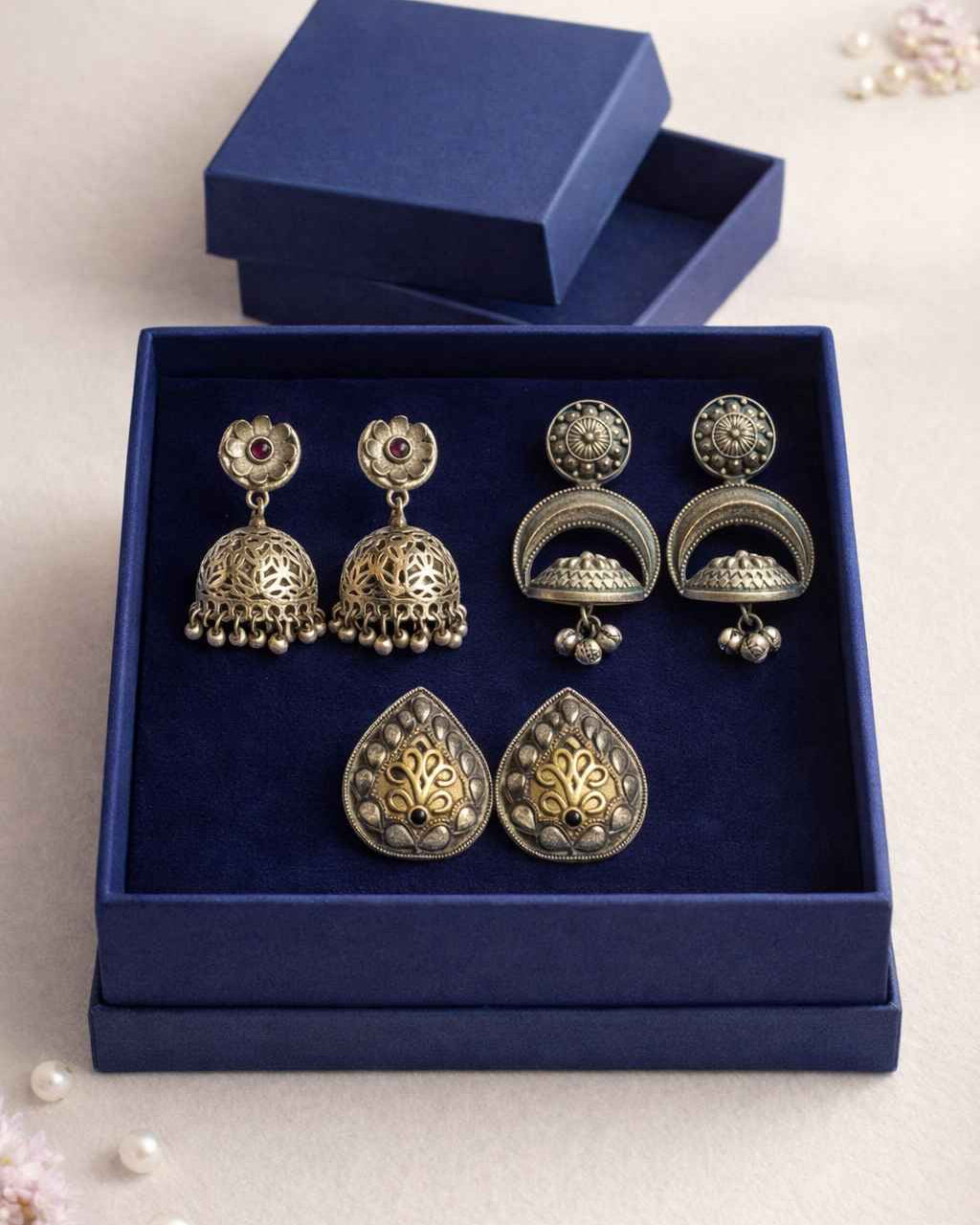 Set of silver and gold earrings in a blue box on a light background