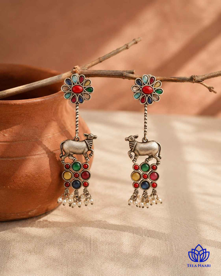 Textured brass surface supports the silver oxidised earring finish.
