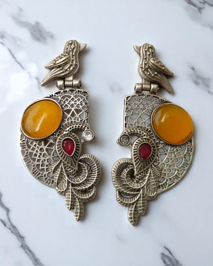 Accents of stone sit within the oxidised silver frame.