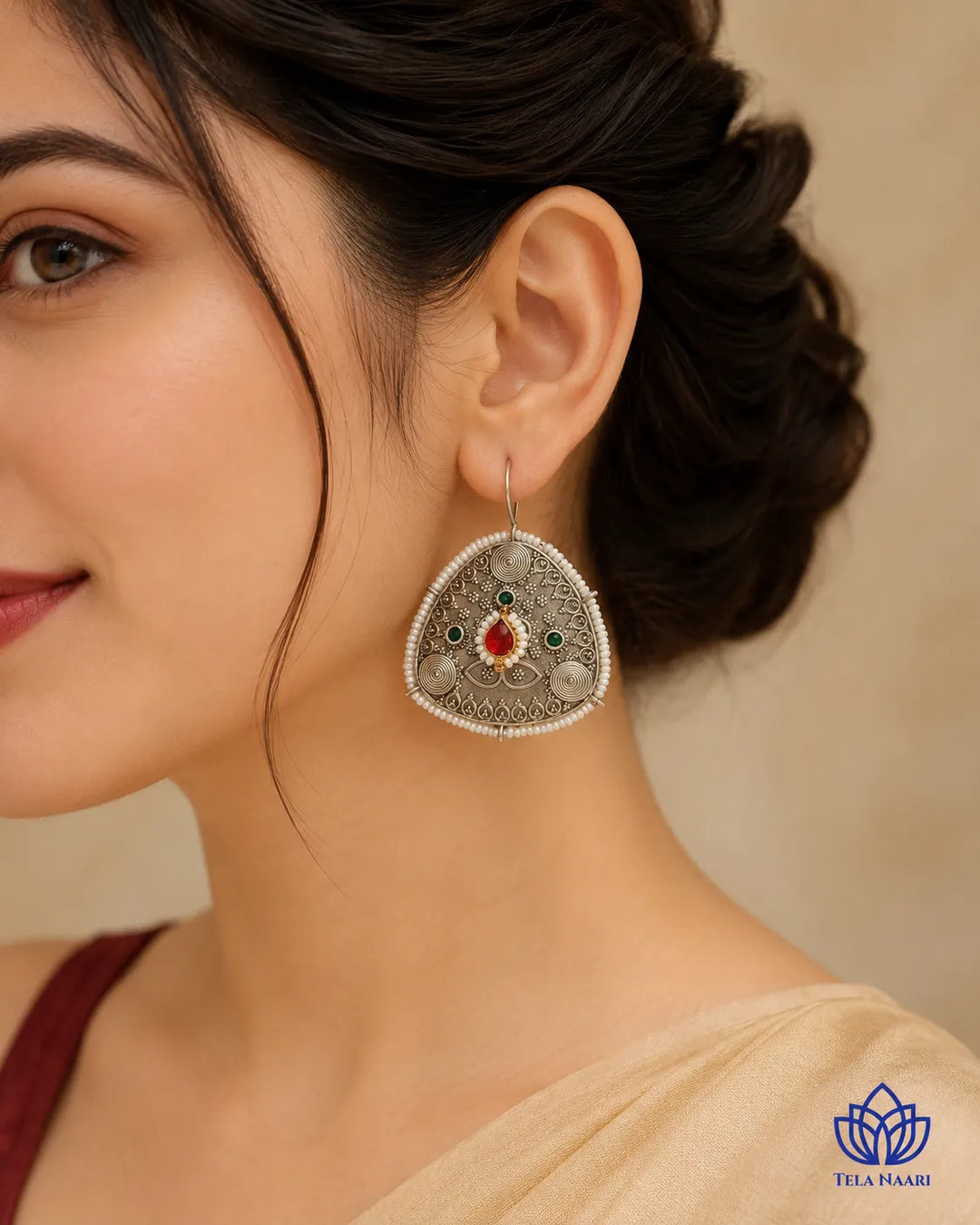 Ruby and pearl accents decorate the surface of this hoop earring.