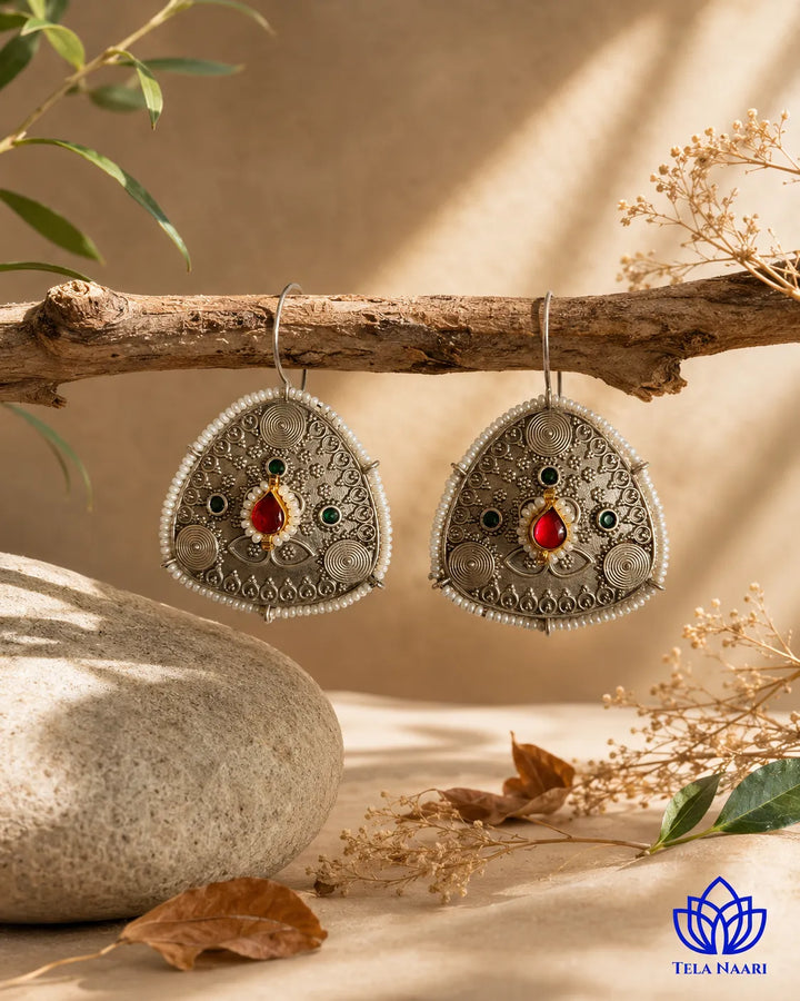 Statement silhouette pairs ruby accents with oxidised silver plating.