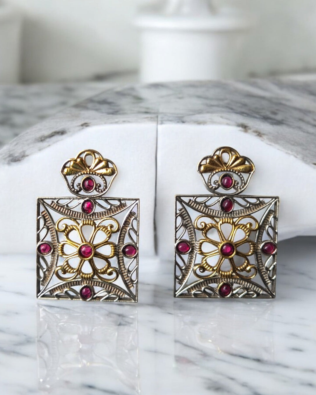Intricate stone work decorates the surface of this square earring.