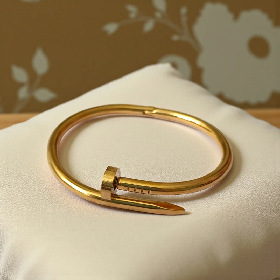Structured cuff silhouette features raised nail-head detailing in anti-tarnish finish.