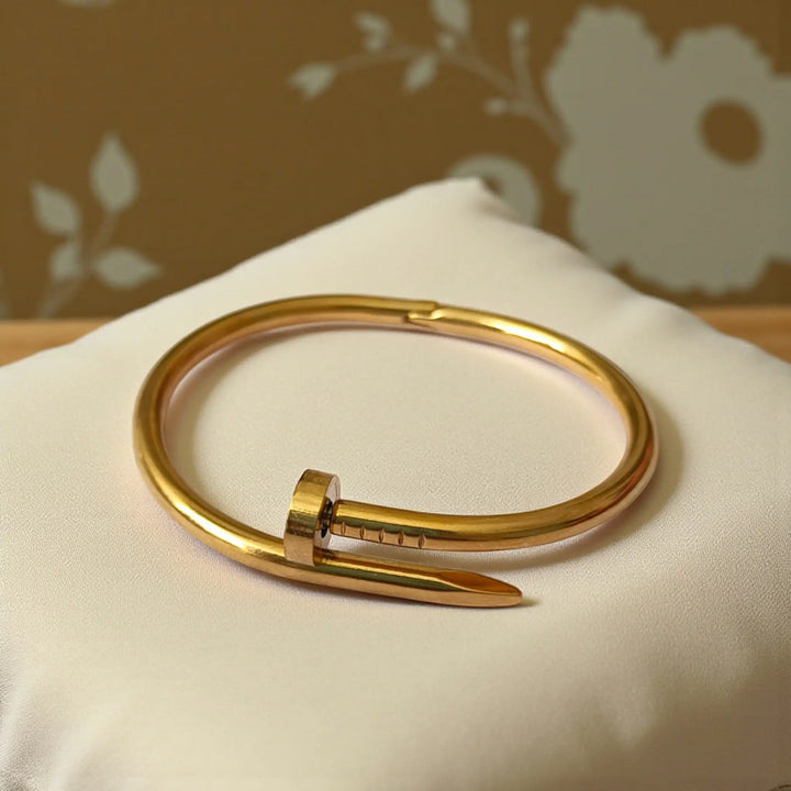 Structured cuff silhouette features raised nail-head detailing in anti-tarnish finish.
