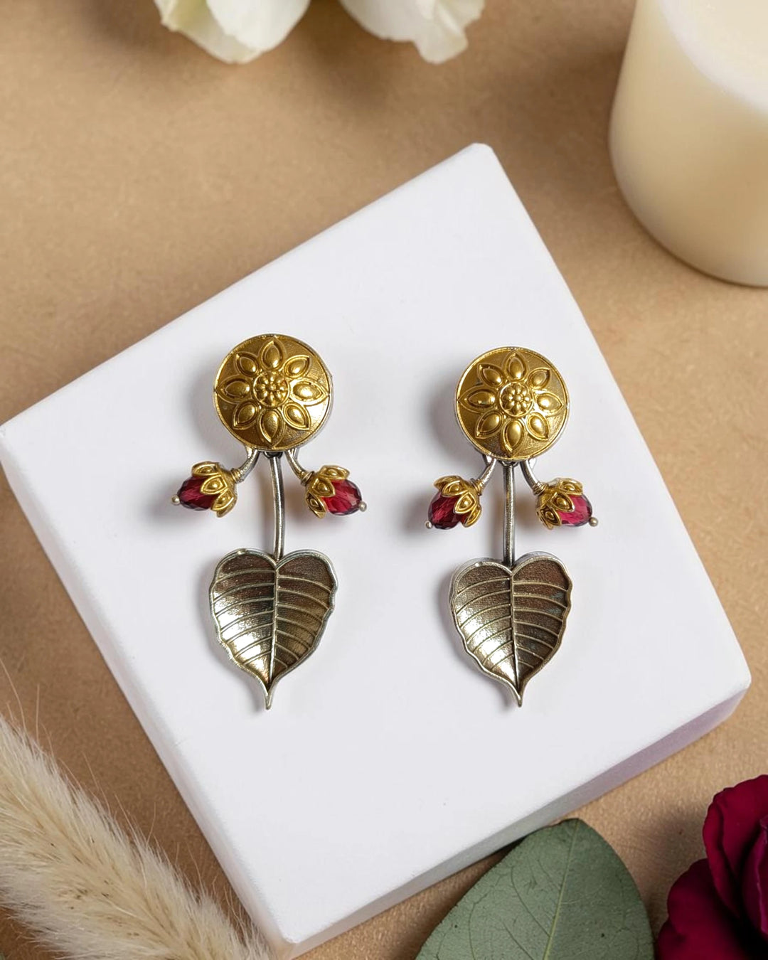 Sunburst motif catches the light across this golden dual-tone drop earring.