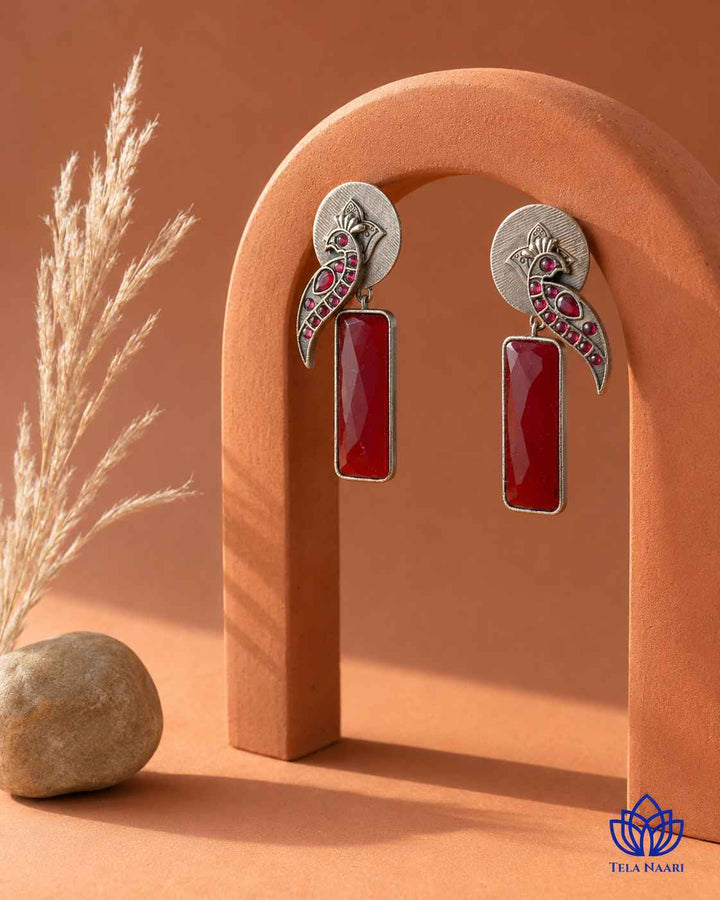 Vivacious red detailing decorates the surface of this earring.