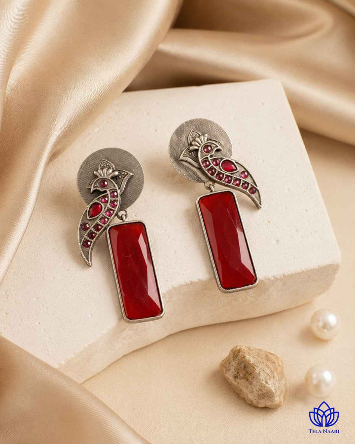 Glass bead detailing decorates the surface of this red earring.