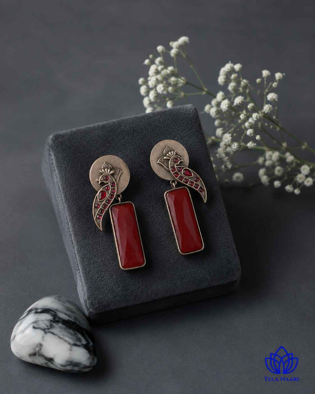 Handmade craftsmanship gives this red earring its intricate charm.