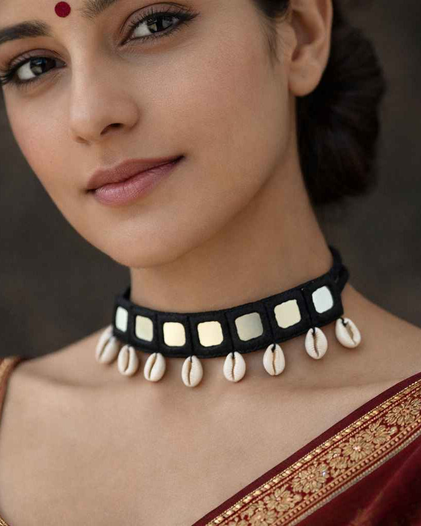 Bold cowrie shells decorate the surface of this black fabric choker.