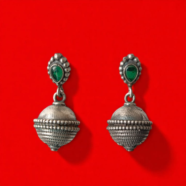 Silver oxidised surface highlights the dangling bell design of this earring.