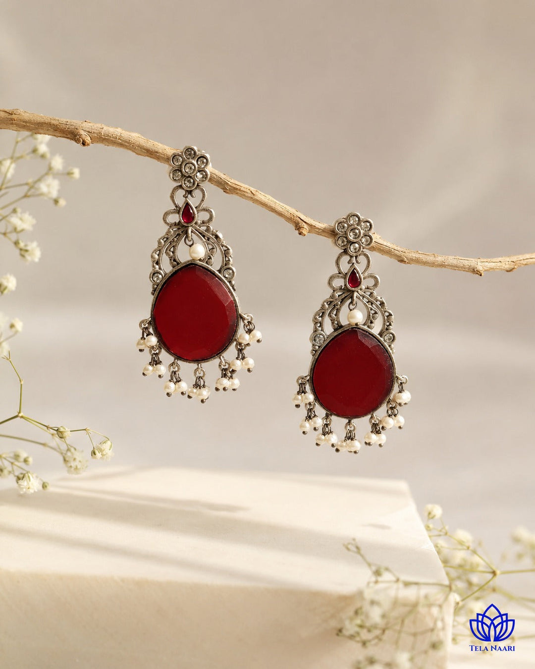 Versatile silhouette pairs red stone detailing with silver plating.