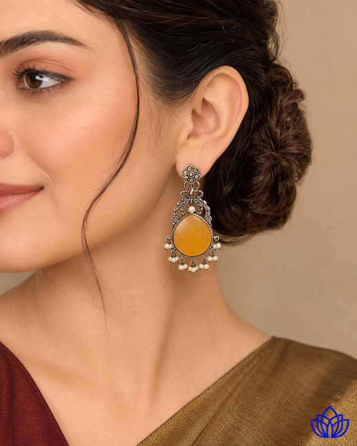 Vivid yellow stone detailing brightens the surface of this earring.