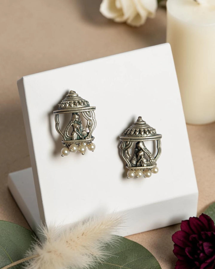 Sacred temple motifs shape the silhouette of this silver-plated earring.
