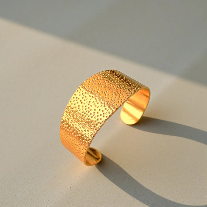 Wide silhouette highlights the dotted texture of this cuff bracelet.
