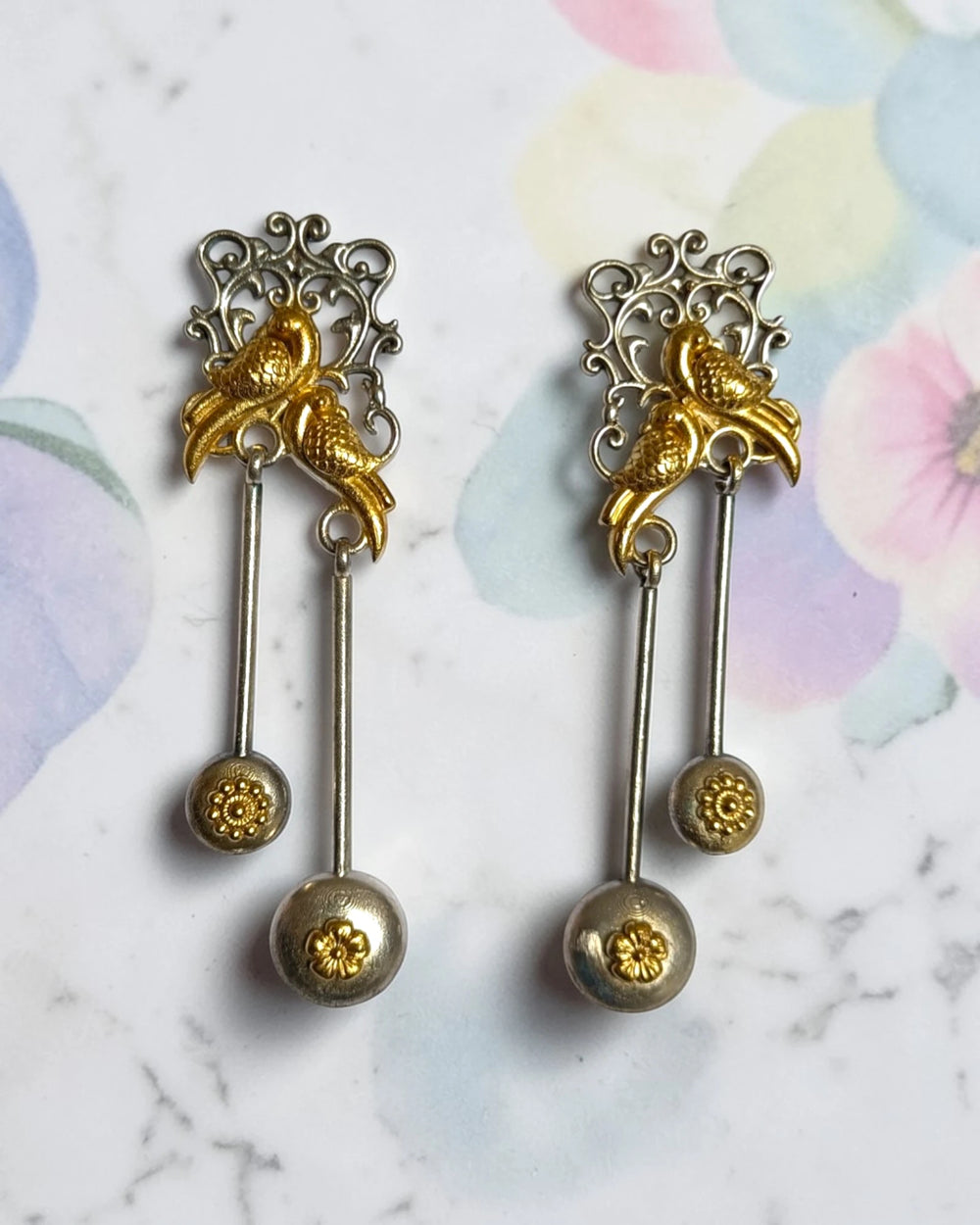 Dual-tone gold finish covers the intricate bird motif of this earring.
