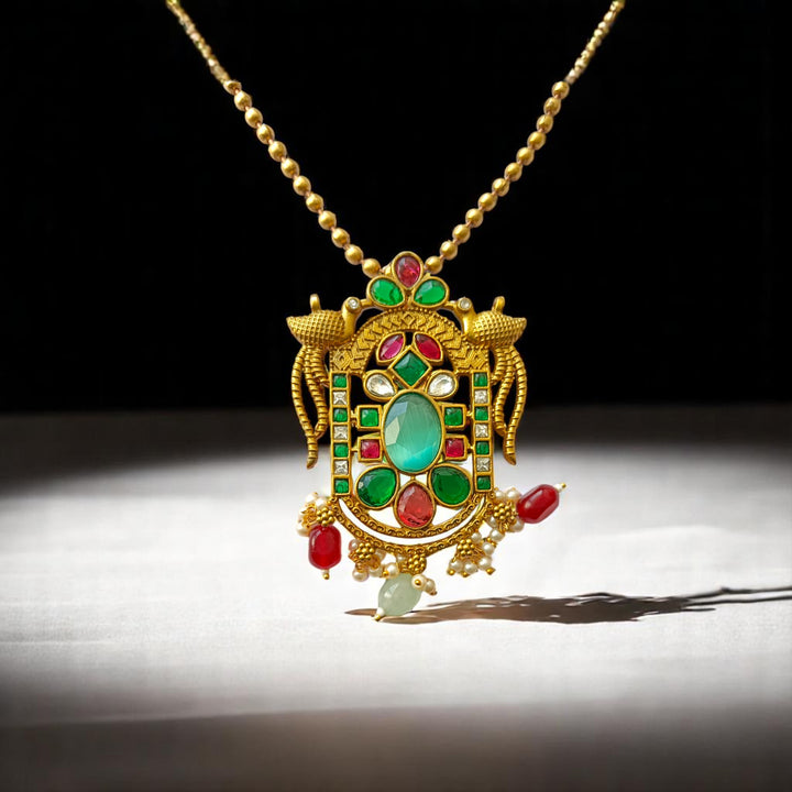Brass construction supports the emerald and ruby stone detailing.