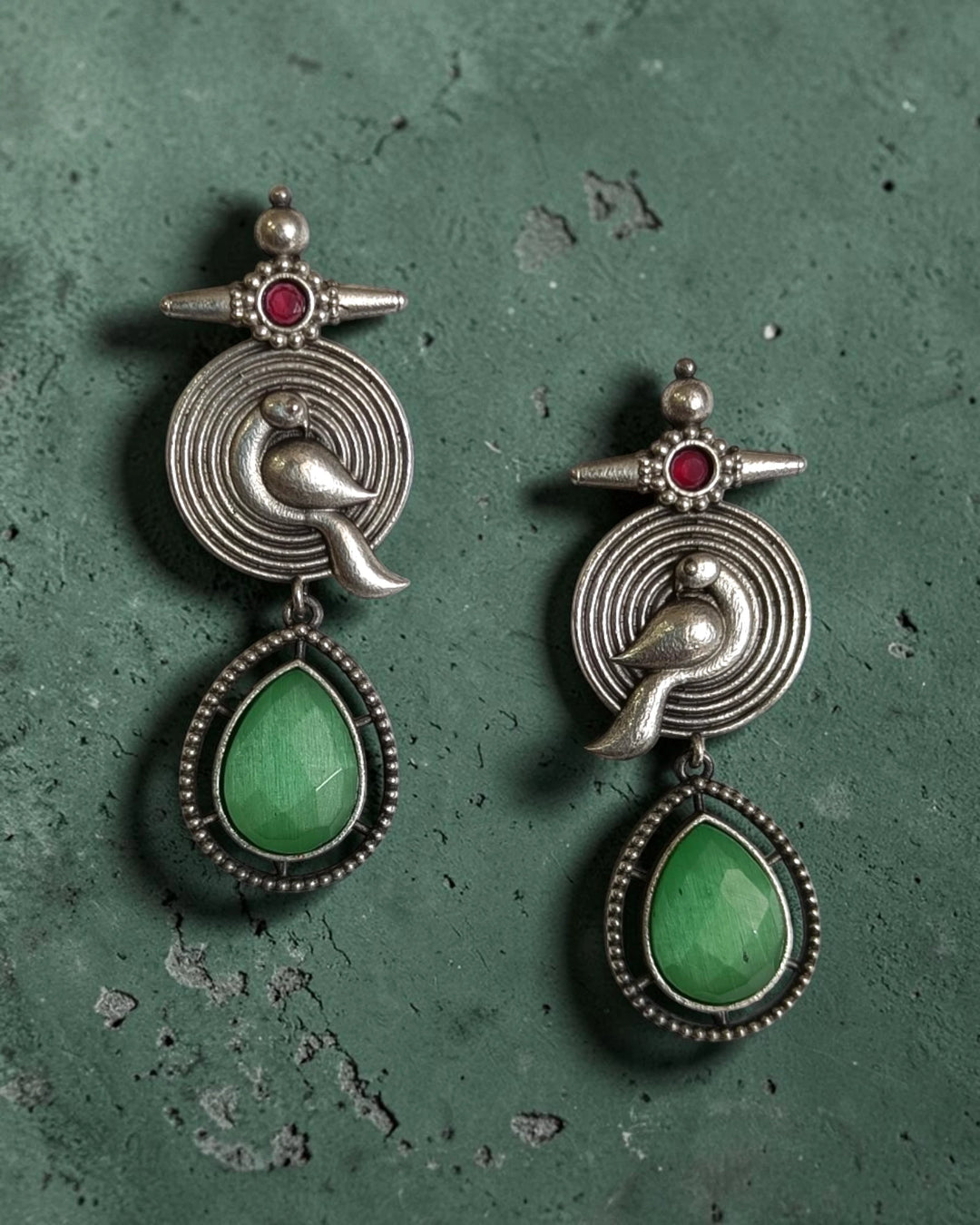 Teardrop-shaped green stone completes the tribal design of this earring.