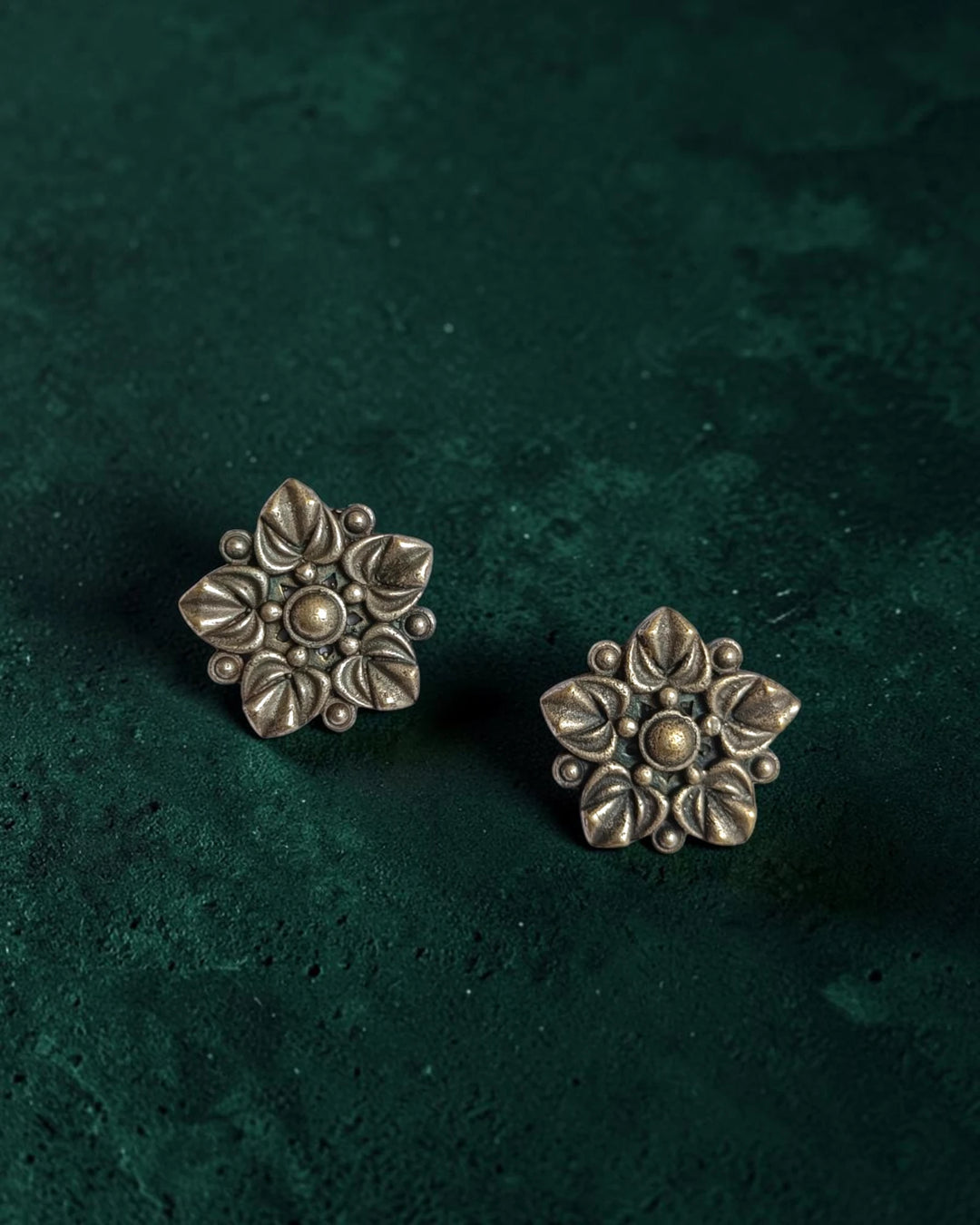 Brass construction supports the intricate floral craftsmanship of this stud.