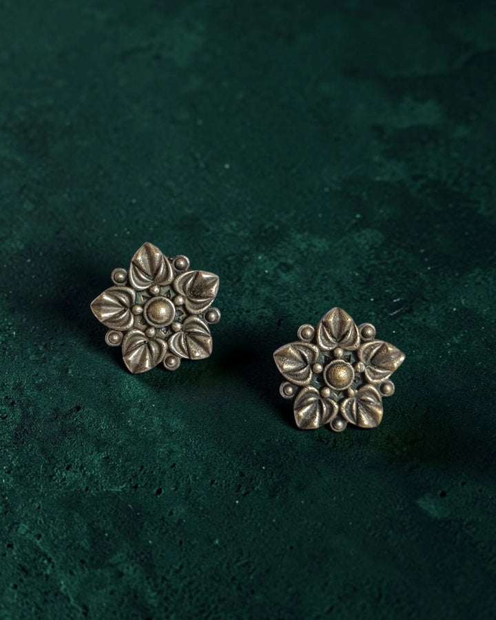 Brass construction supports the intricate floral craftsmanship of this stud.