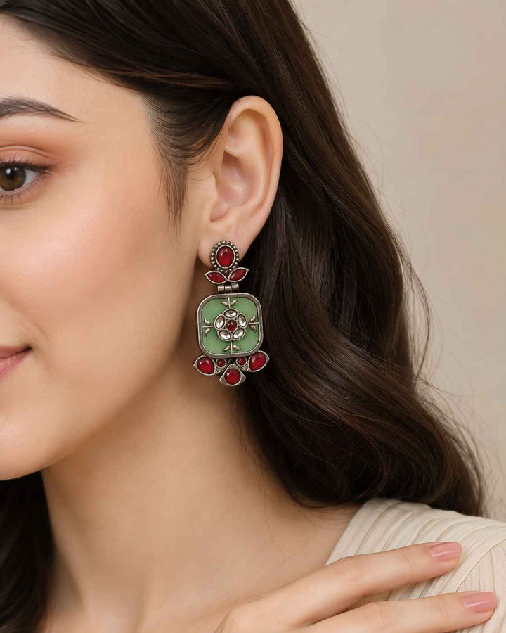 Free-moving dangler silhouette pairs brass with a silver-plated finish.