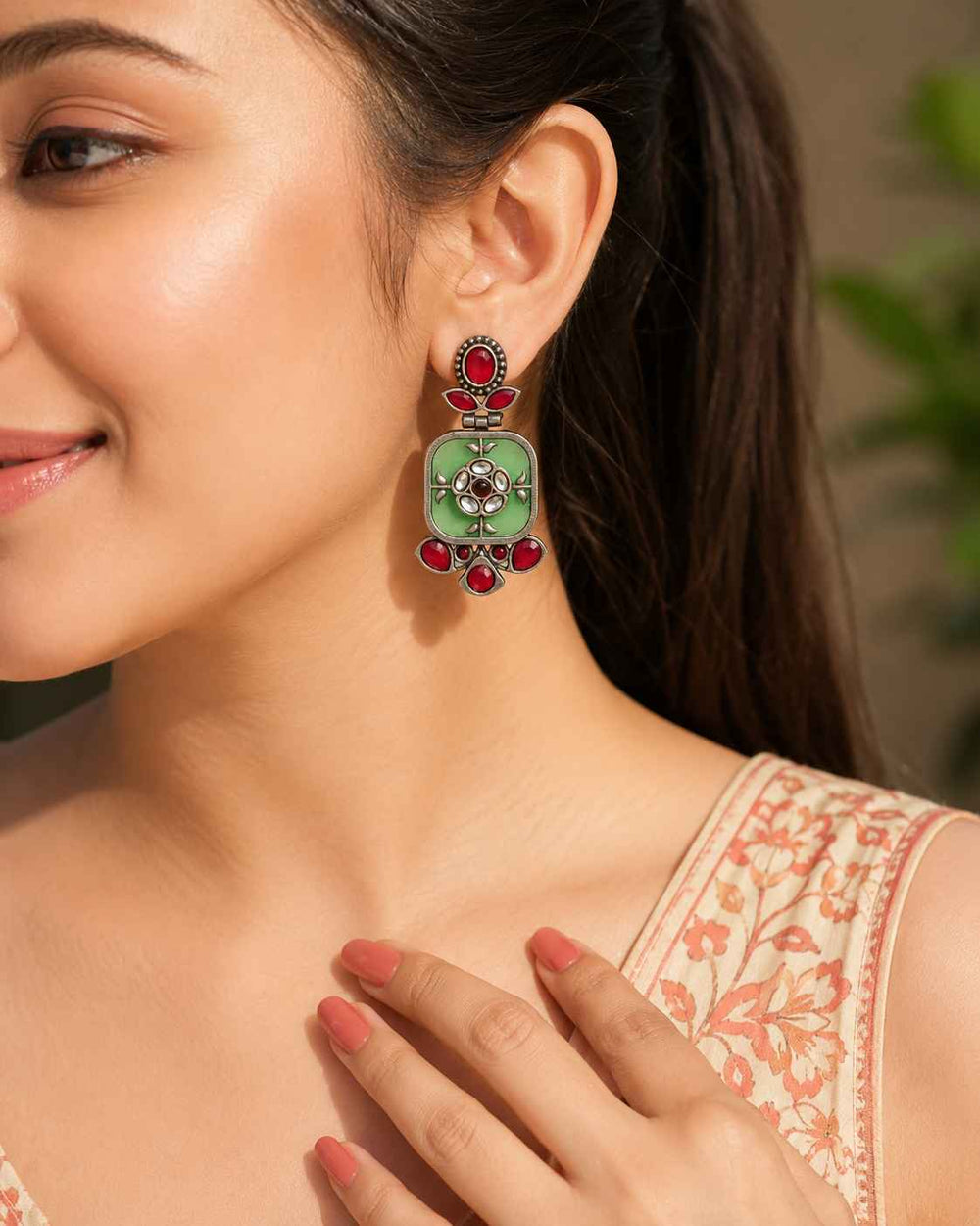 Brass construction supports this silver-plated green dangler earring.