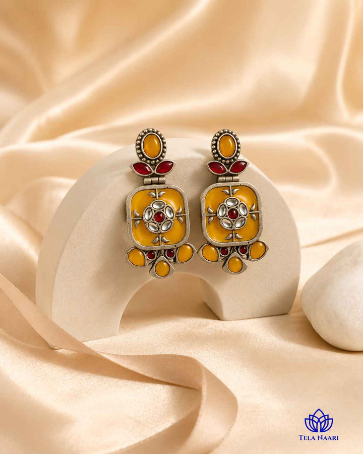 Golden-yellow hues brighten the silver-plated surface of this earring.