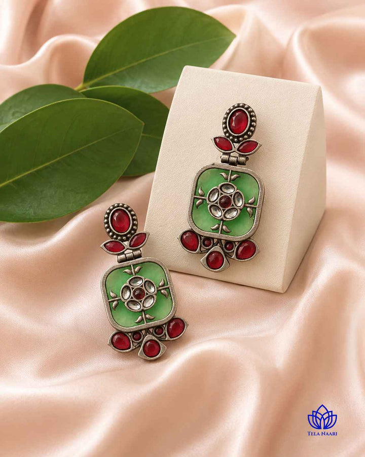 Delicate brass earring carries a silver-plated green finish.