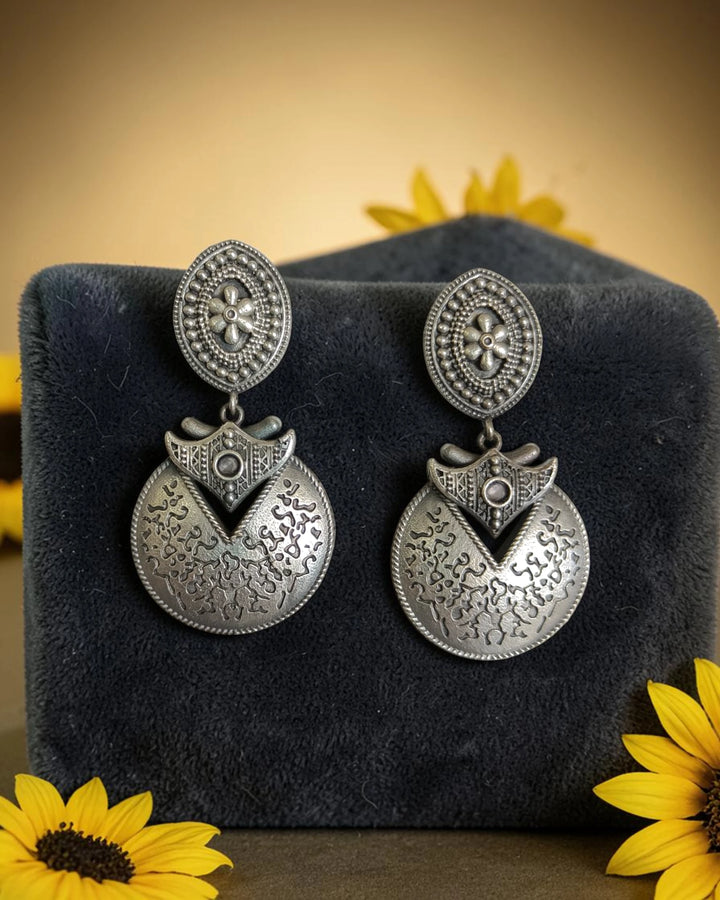 Silver oxidised finish covers the surface of this disk earring.