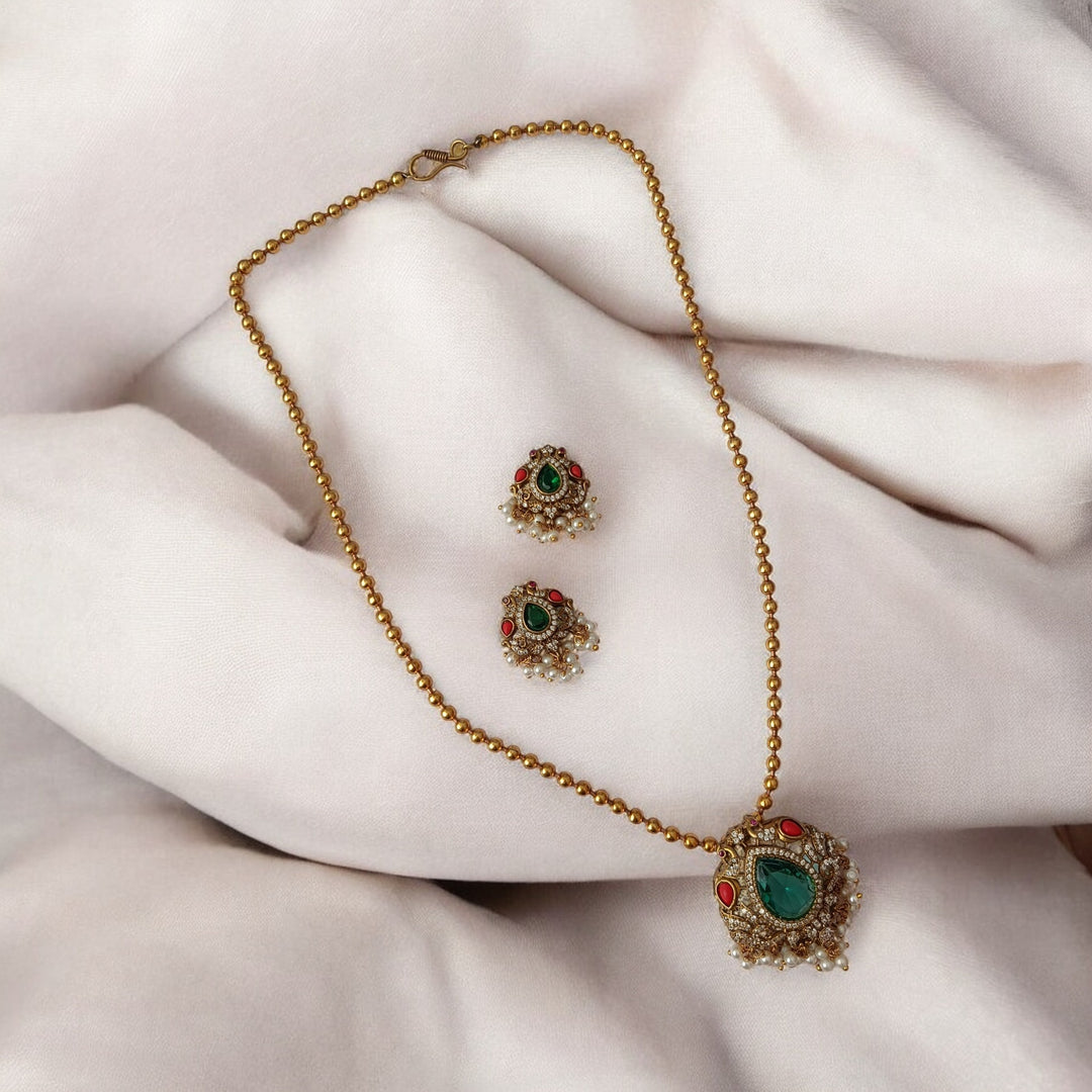 Elegant pendant silhouette pairs green stone with dual-tone plating.