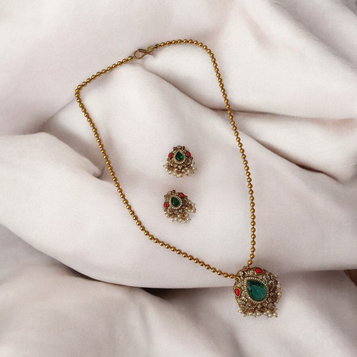 Elegant pendant silhouette pairs green stone with dual-tone plating.