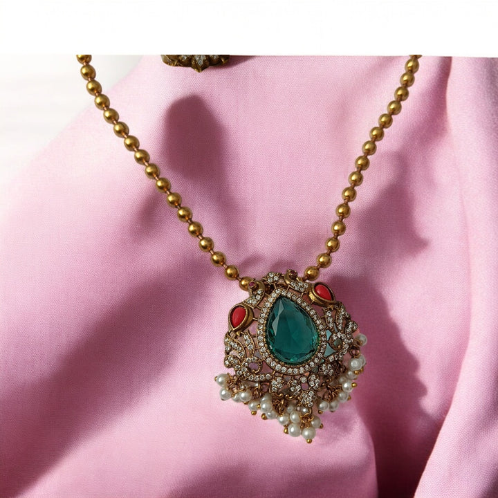 Timeless design combines a green stone pendant with dual-tone plating.