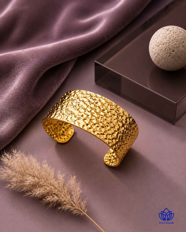 Polished gold surface reflects the striking hammered detail throughout.
