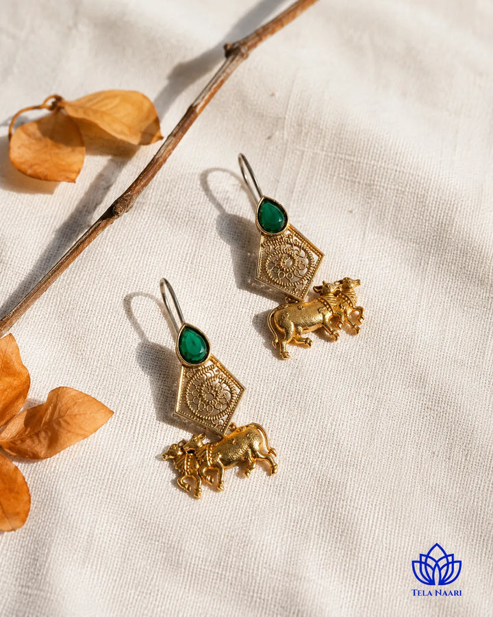Lustrous emerald-toned accents highlight this cow motif earring.