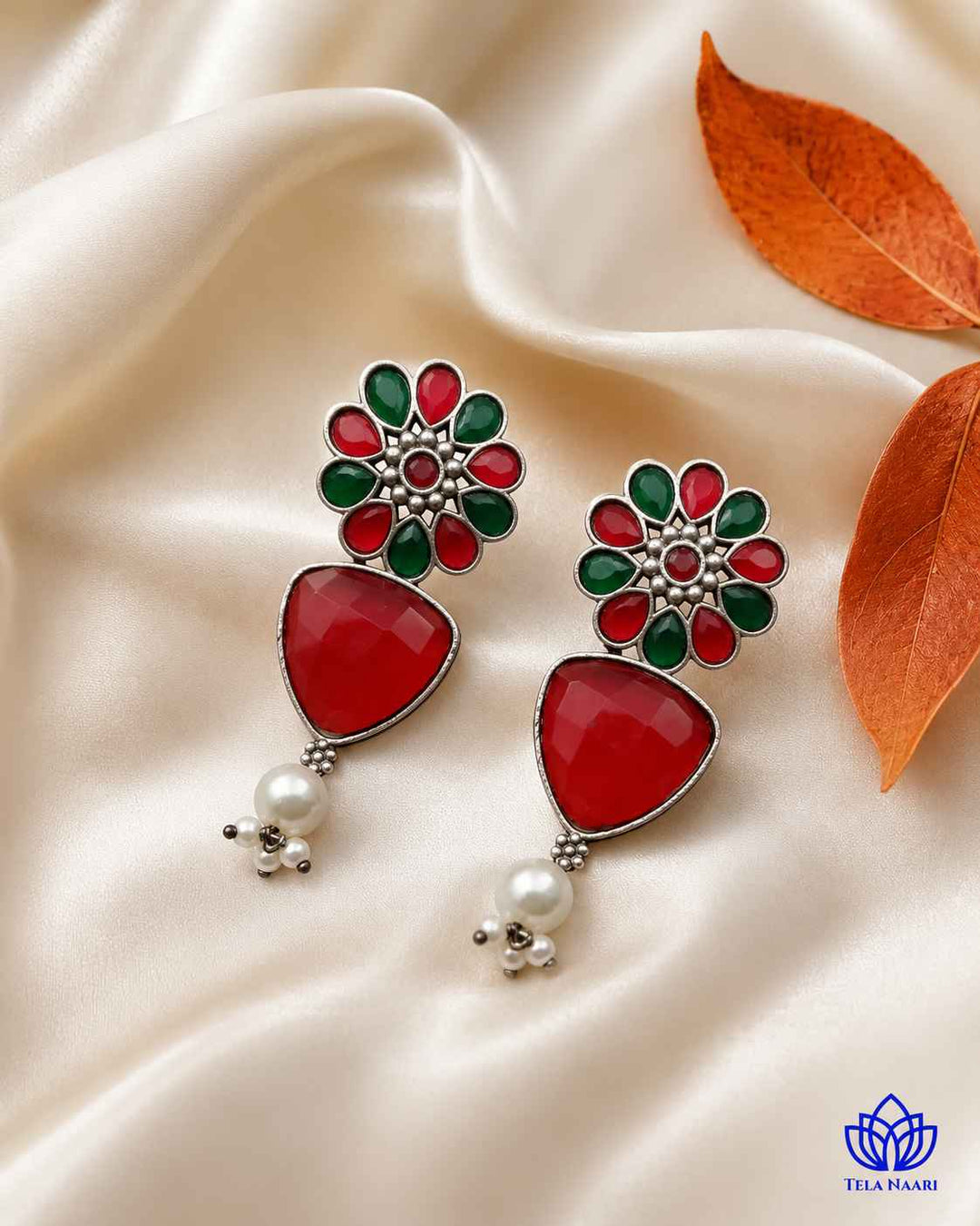 Polished red and green tones define this silver-plated earring.
