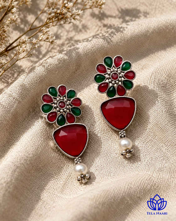 Brass construction forms the base of this red-toned earring.
