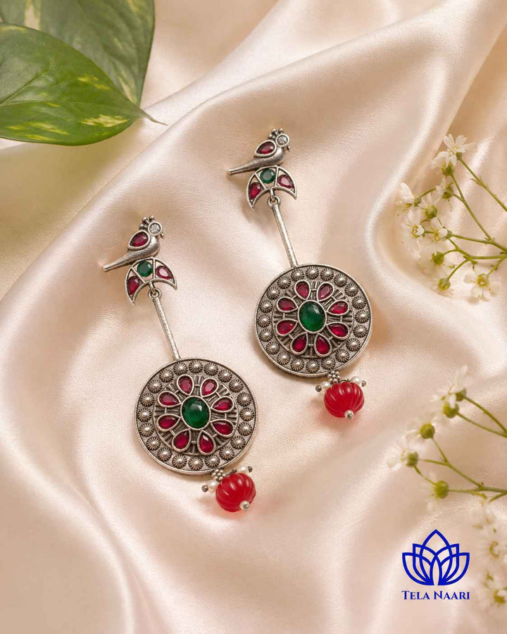 Red and green stone accents sit within the bird-shaped earring.