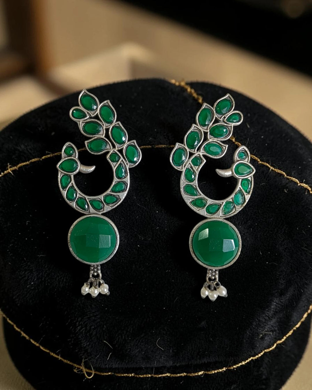 Striking peacock detailing shapes the silhouette of this earring.