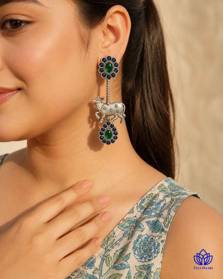 Compact three-inch earring pairs oxidised silver with a Nandi motif.