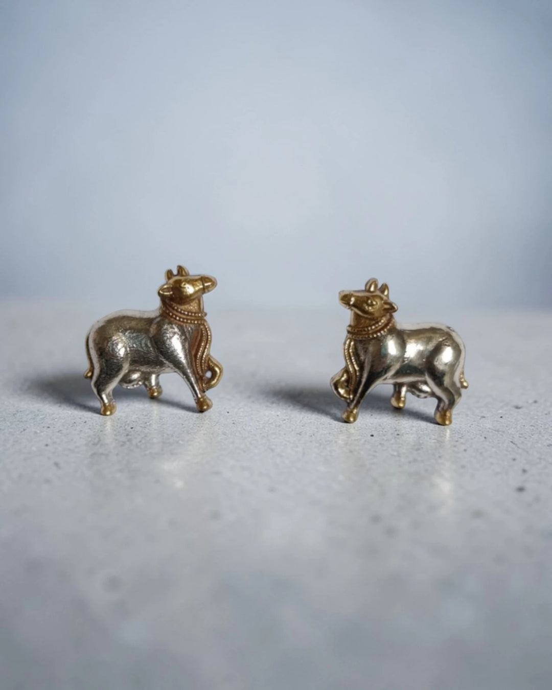 Sacred Kamdhenu cow symbolism shapes this dual-tone stud earring.