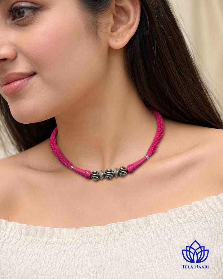 Polished finish highlights the pink thread silhouette of this choker.