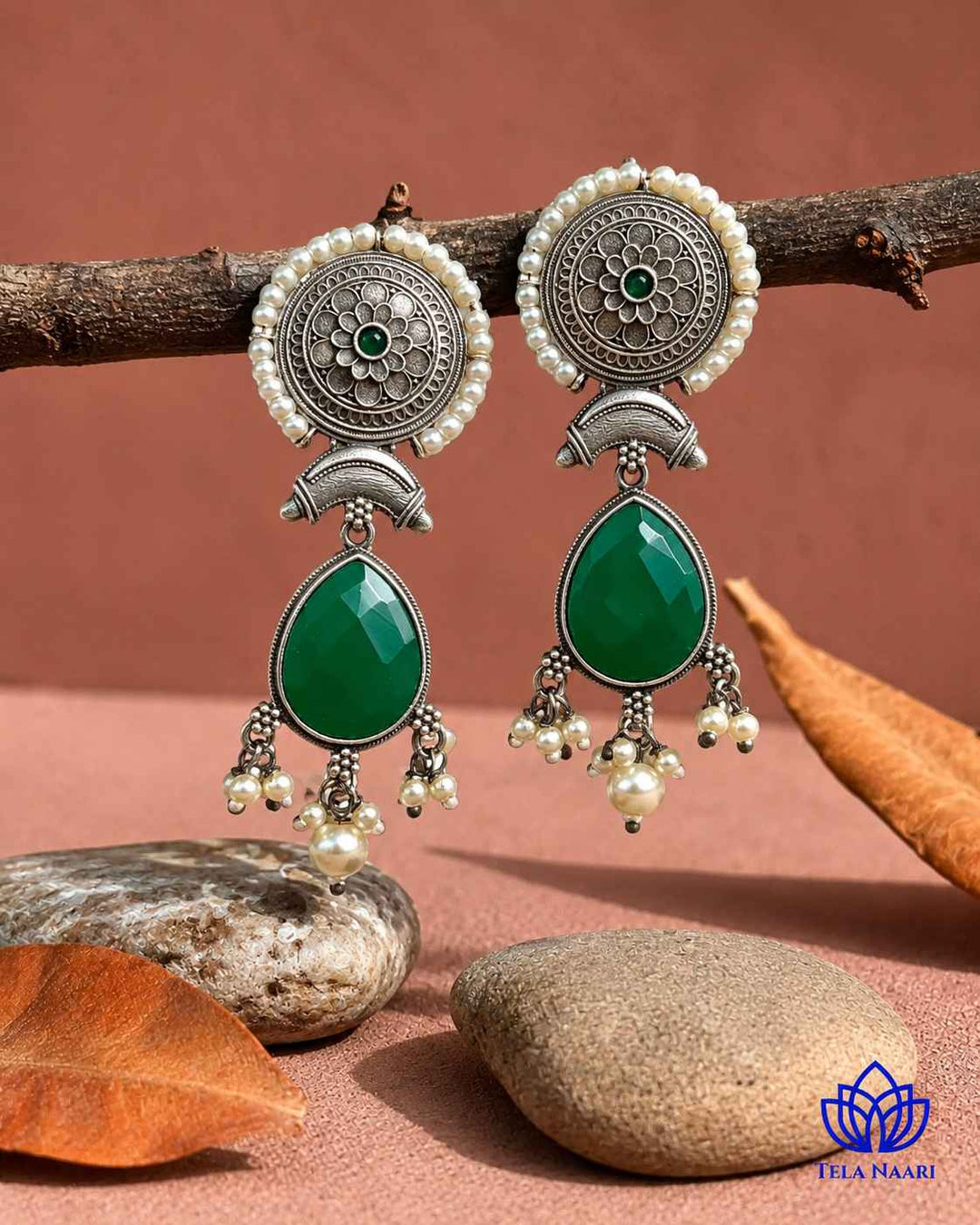 Earthy red and green stone accents sit at the centre of this earring.