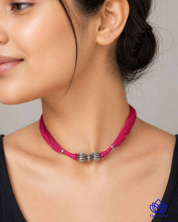 Delicate pink thread detailing shapes this silver-plated choker.