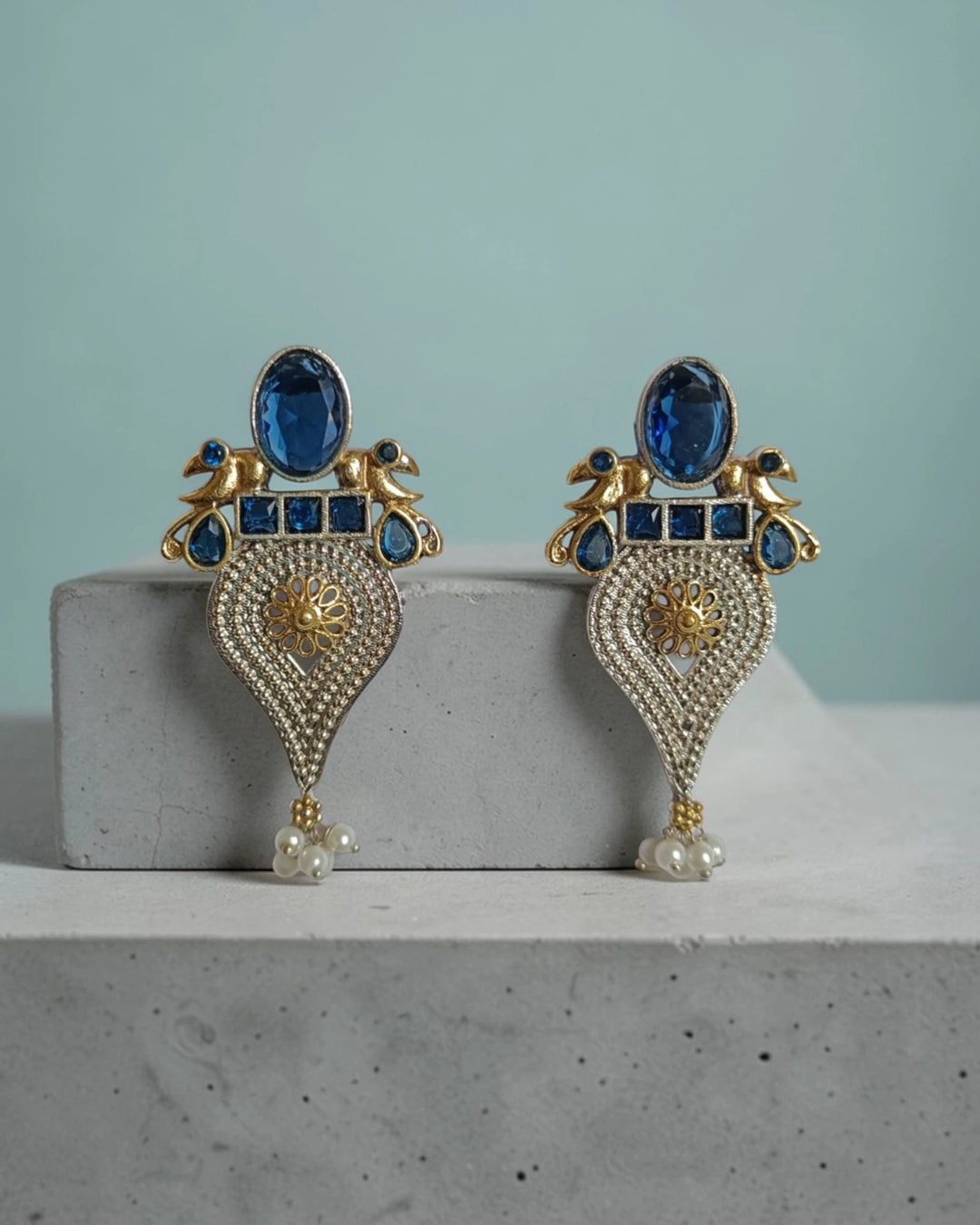 Regal peacock detailing shapes the silhouette of this blue earring.