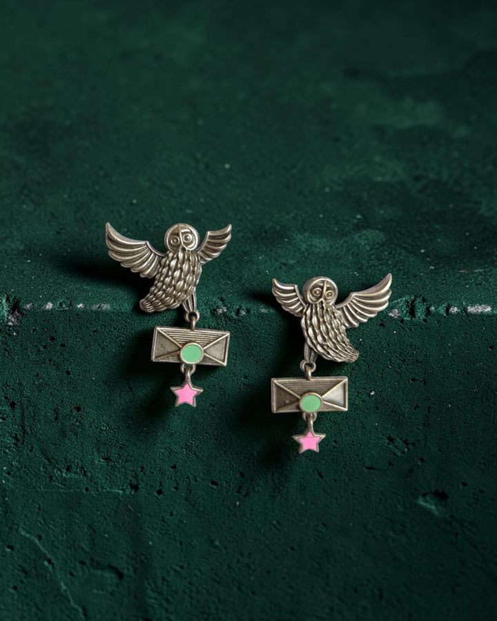 Sea green accents highlight the surface of this owl-motif earring.