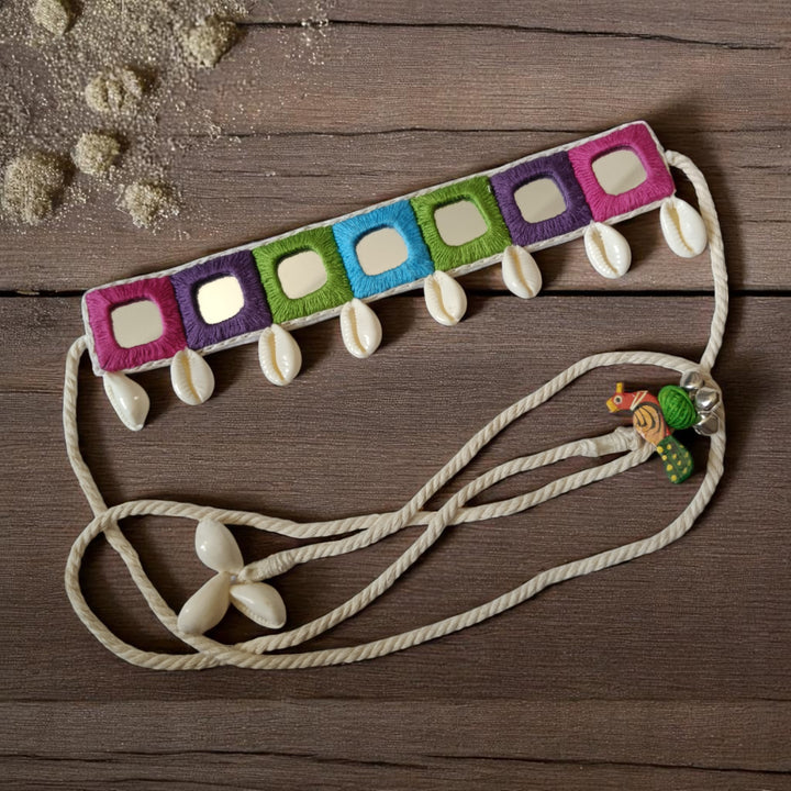 Authentic cowrie shells decorate the surface of this fabric choker.