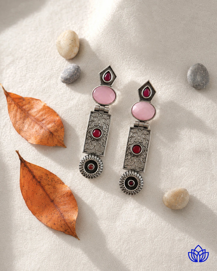 Handcrafted metalwork gives this pink earring its artisanal charm.