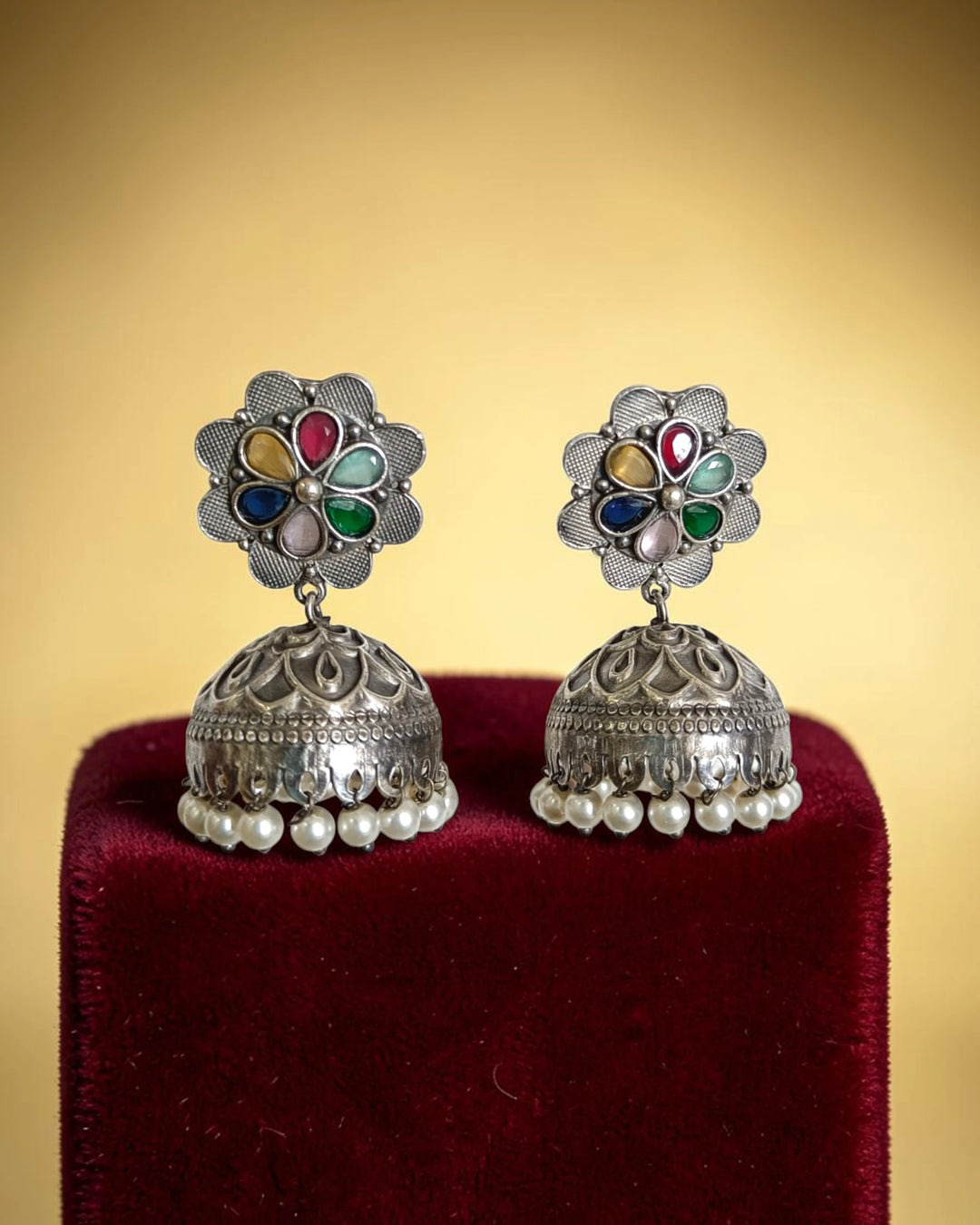 Brass construction supports the ethnic detailing of this jhumka earring.