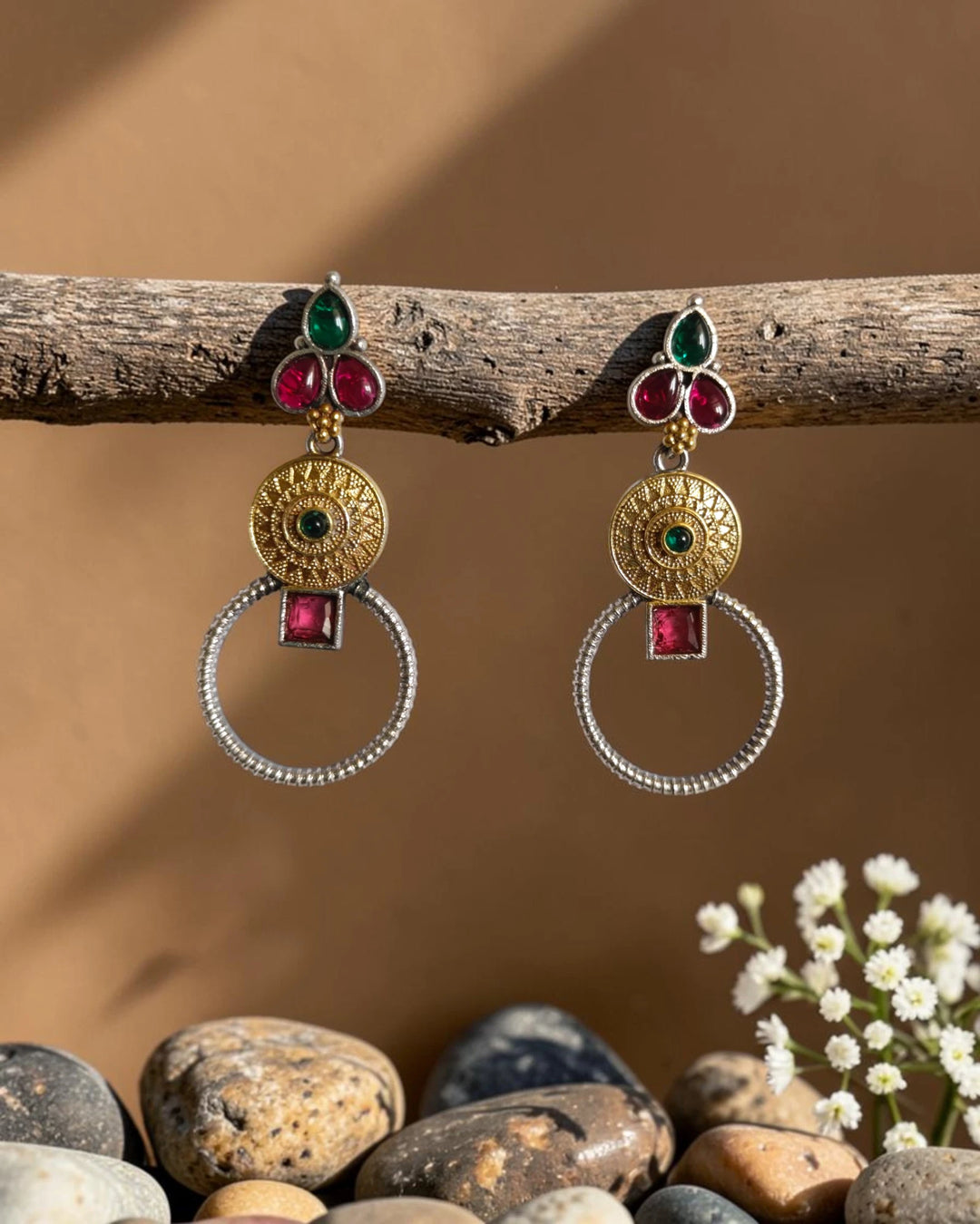 Ruby red and green stones sit at the centre of this earring.