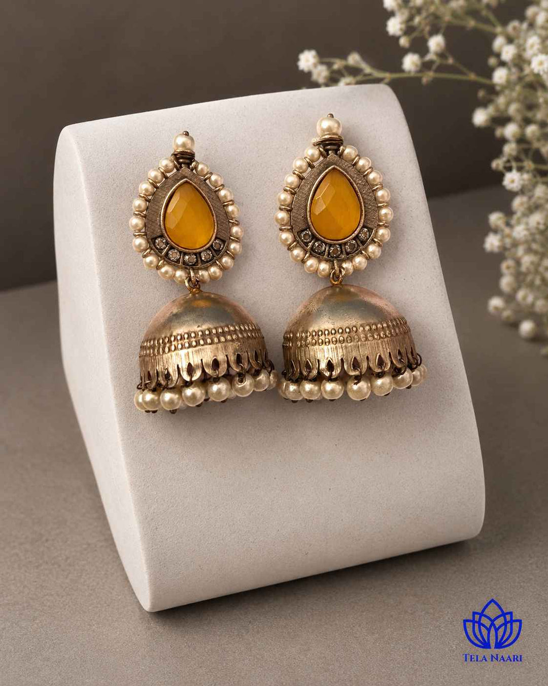 Graceful jhumka silhouette highlights this yellow glass bead earring.
