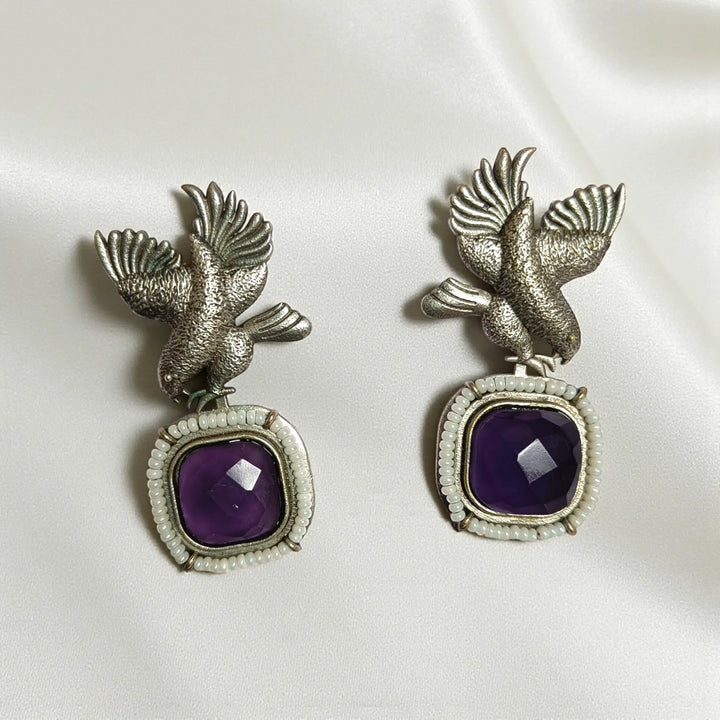 Glass bead detailing decorates the surface of this bird earring.
